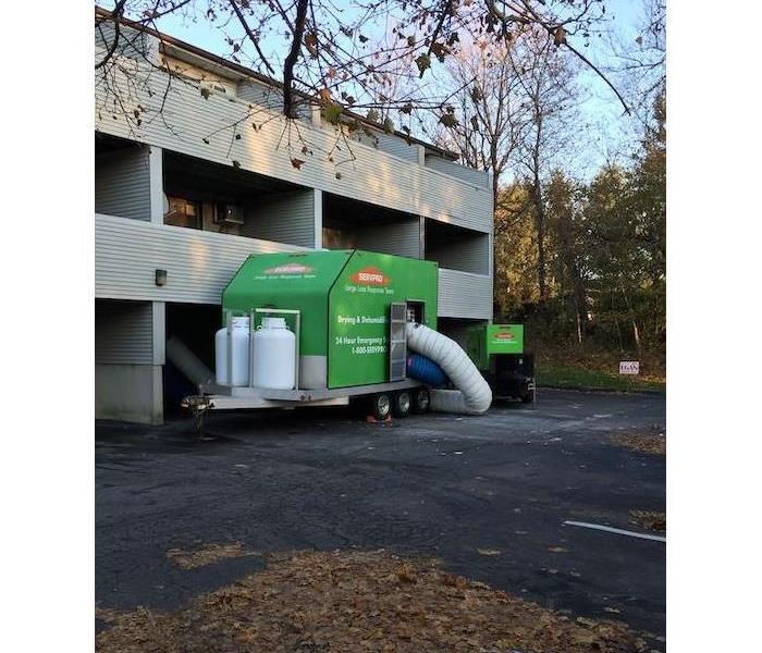 SERVPRO drying and dehumidification unit in front of condos