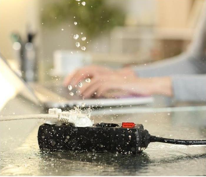 person working on computer, water dripping on outlet