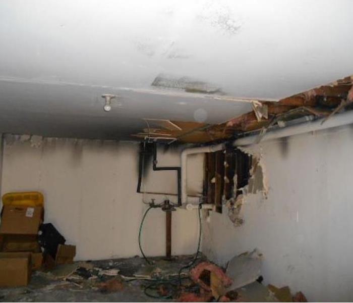 Room with fire damage and hole in a ceiling